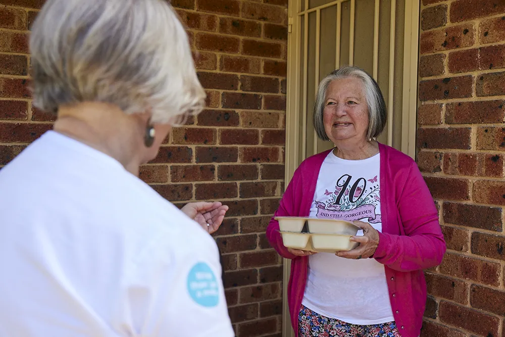 meals on wheels driver delivering a meal to lady
