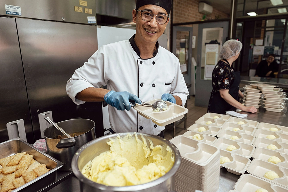 meals on wheels volunteer serving mashed potatoes